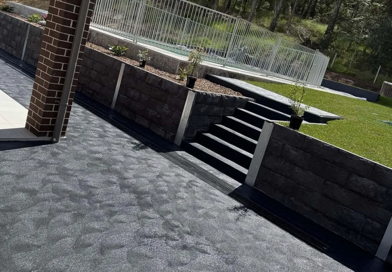 Exposed aggregate path beside a block retaining wall and garden